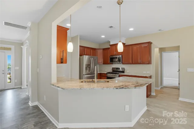 a kitchen with stainless steel appliances granite countertop a sink a stove and a granite counter tops with wooden floors