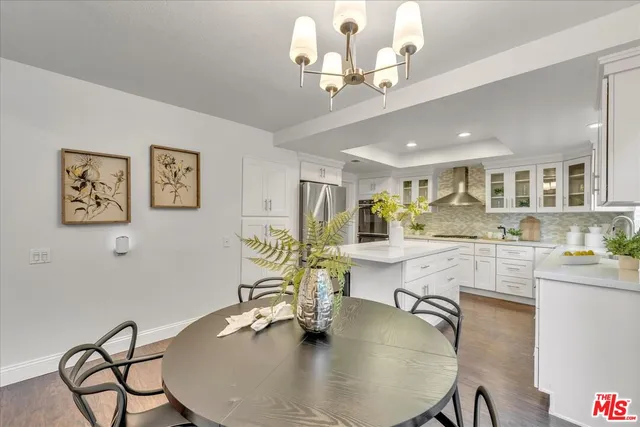 a dining room with wooden floor a chandelier a wooden table and chairs