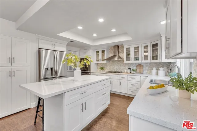 a kitchen with stainless steel appliances kitchen island granite countertop a refrigerator and a sink