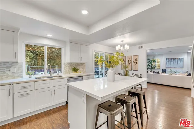 a large white kitchen with granite countertop lots of counter top space and dining table