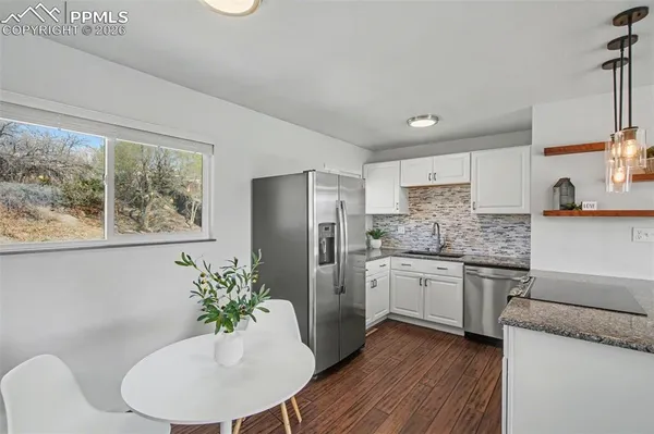a kitchen with stainless steel appliances granite countertop a refrigerator a sink a stove a dining table and chairs