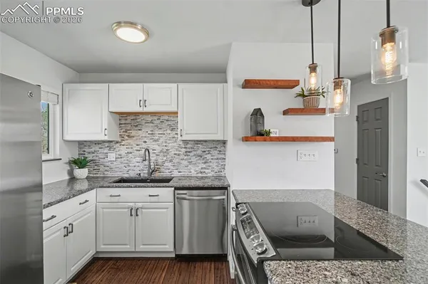 a kitchen with stainless steel appliances granite countertop a sink a stove and a wooden floors