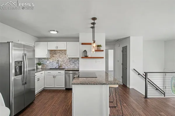a kitchen with stainless steel appliances granite countertop a refrigerator a stove and a wooden floors