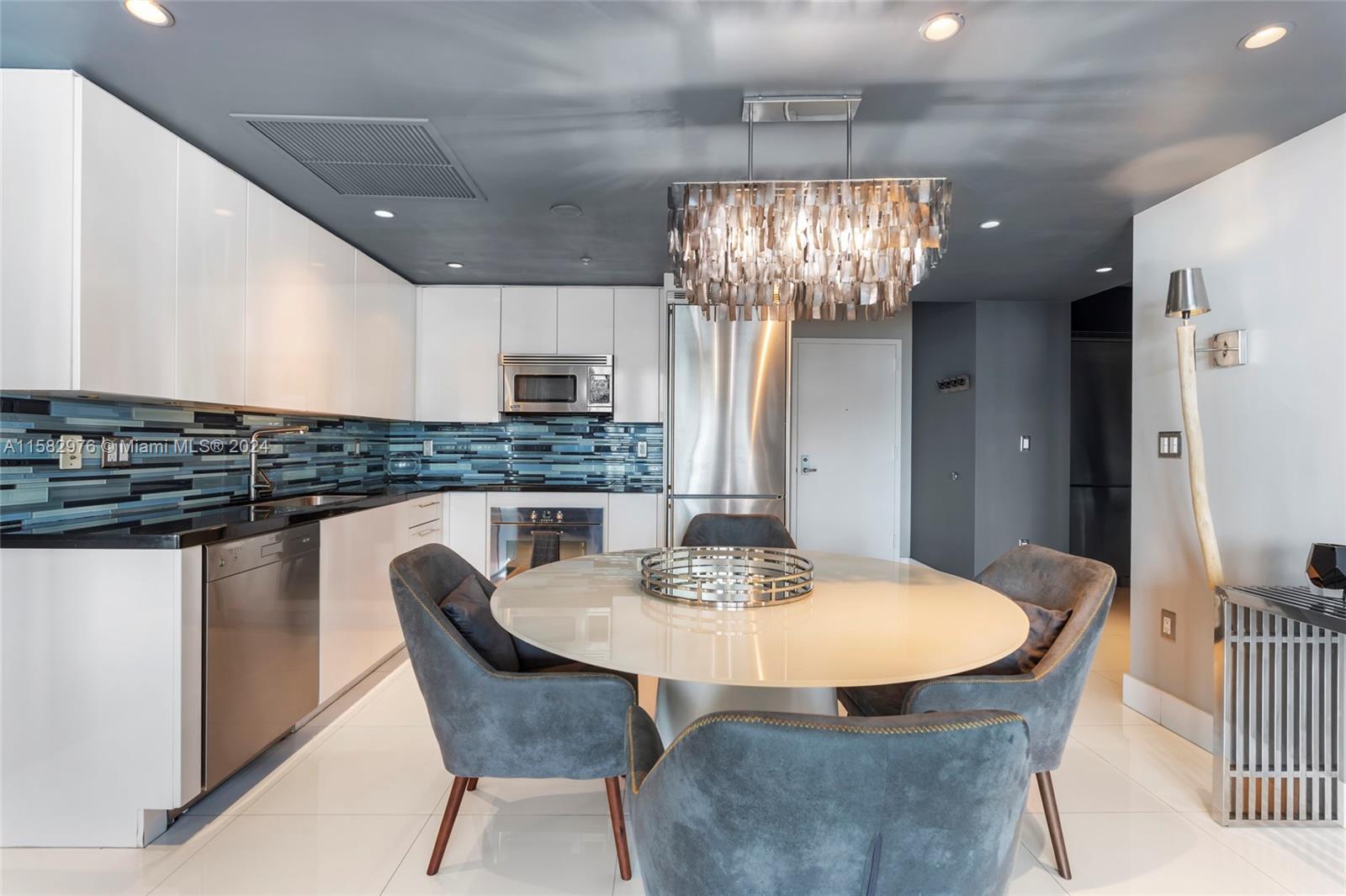 92 Southwest 3rd Street, Unit 2303 Miami, FL 33130 - Photo 14 of 35 a kitchen with stainless steel appliances granite countertop a dining table chairs and white cabinets