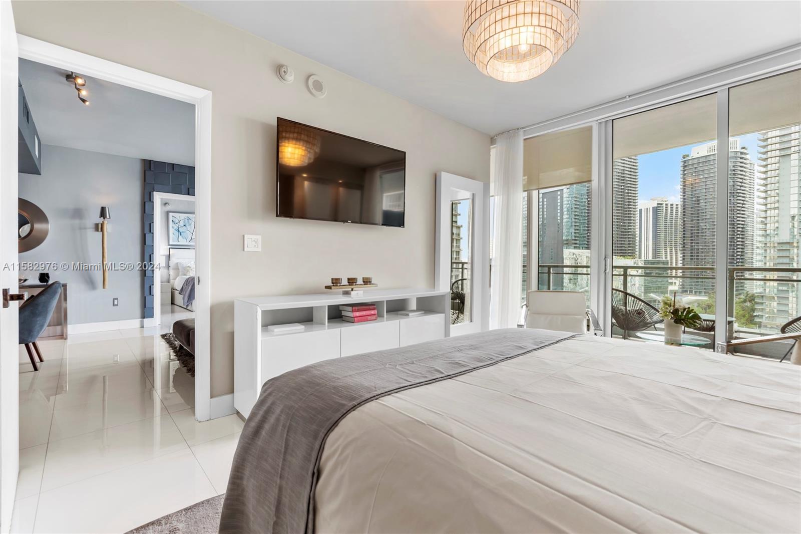 92 Southwest 3rd Street, Unit 2303 Miami, FL 33130 - Photo 19 of 35 a bedroom with a bed a flat screen tv and a large window