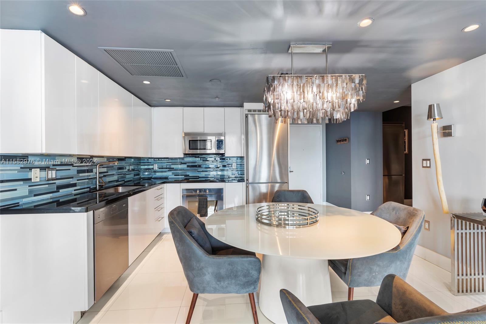 92 Southwest 3rd Street, Unit 2303 Miami, FL 33130 - Photo 4 of 35 a kitchen with stainless steel appliances kitchen island granite countertop a dining table chairs and a refrigerator
