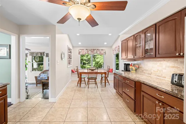 a kitchen with stainless steel appliances kitchen island granite countertop a refrigerator a sink a dining table and chairs with wooden floor