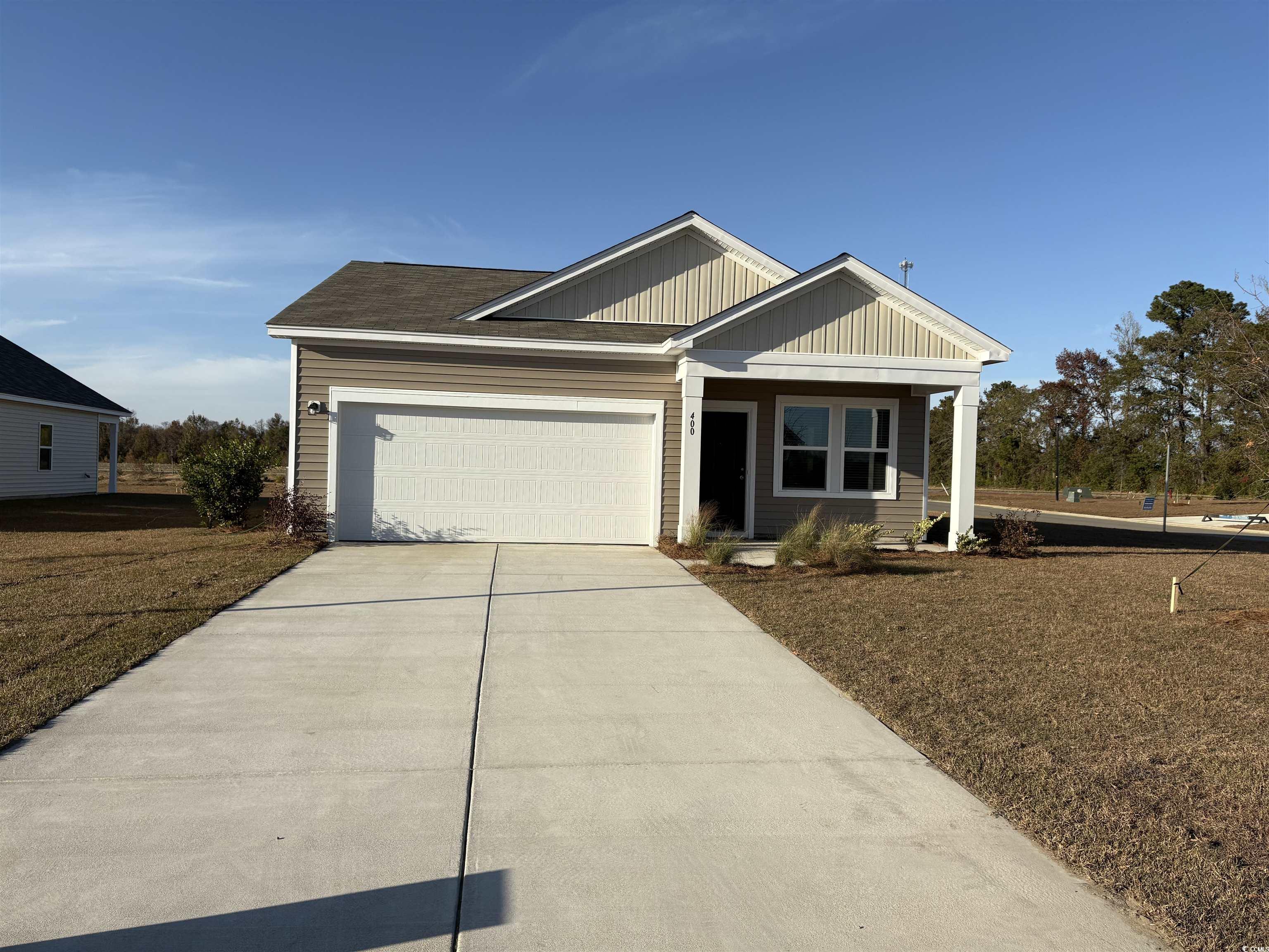 View of front of home with driveway, an attached garage, a porch, and board and batten siding