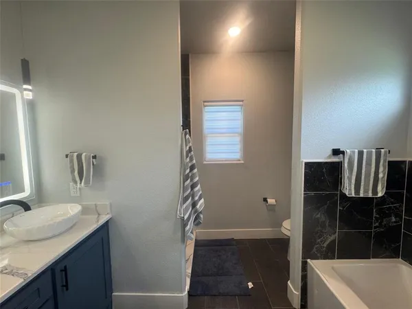 a bathroom with a granite countertop sink a toilet and tub