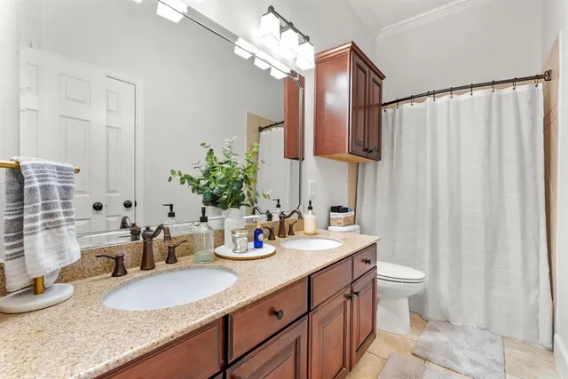 a bathroom with double vanity sinks a toilet a mirror and shower