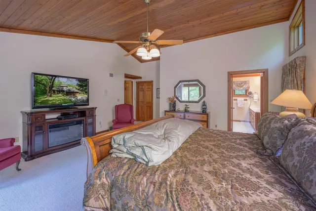 a bed room with a bed mirror and a flat tv screen on dresser
