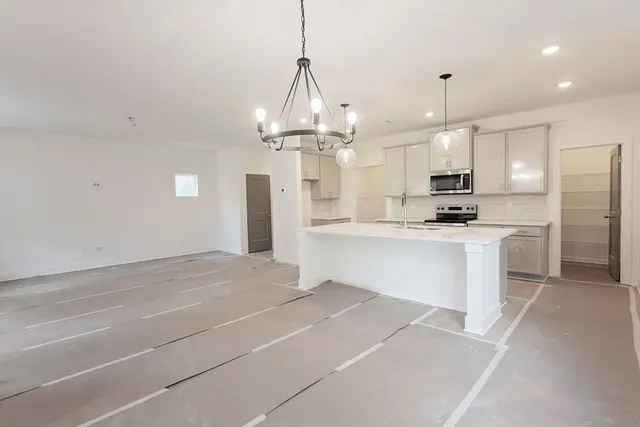 a large kitchen with kitchen island white cabinets and stainless steel appliances