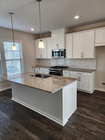 a kitchen with kitchen island granite countertop a sink a counter space appliances and cabinets