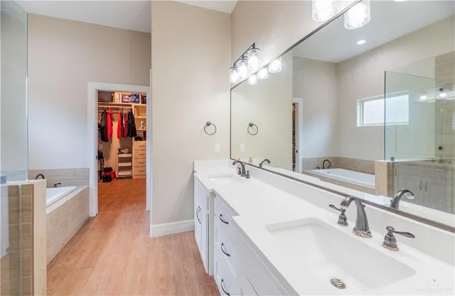 a spacious bathroom with a bathtub double sink and mirrors