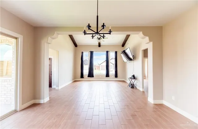 a view of an empty room with window and wooden floor