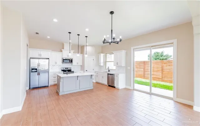 a large kitchen with cabinets wooden floor white stainless steel appliances and view living room