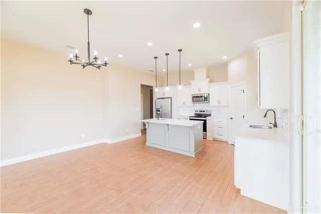 a large white kitchen with a large window a sink and stainless steel appliances