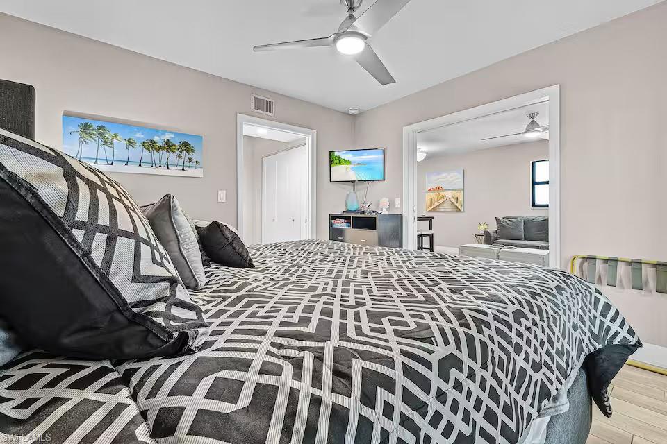 600 Neapolitan Way, Unit 341 Naples, FL 34103 - Photo 11 of 28 a large bedroom with a bed and wooden floor