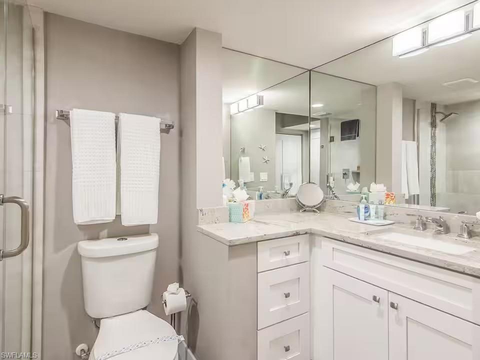 600 Neapolitan Way, Unit 341 Naples, FL 34103 - Photo 12 of 28 a bathroom with a toilet a sink a mirror a vanity and shower