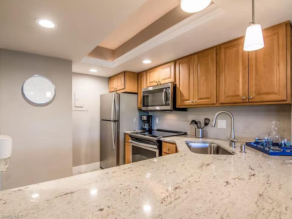 600 Neapolitan Way, Unit 341 Naples, FL 34103 - Photo 7 of 28 a kitchen with stainless steel appliances granite countertop a refrigerator sink and cabinets