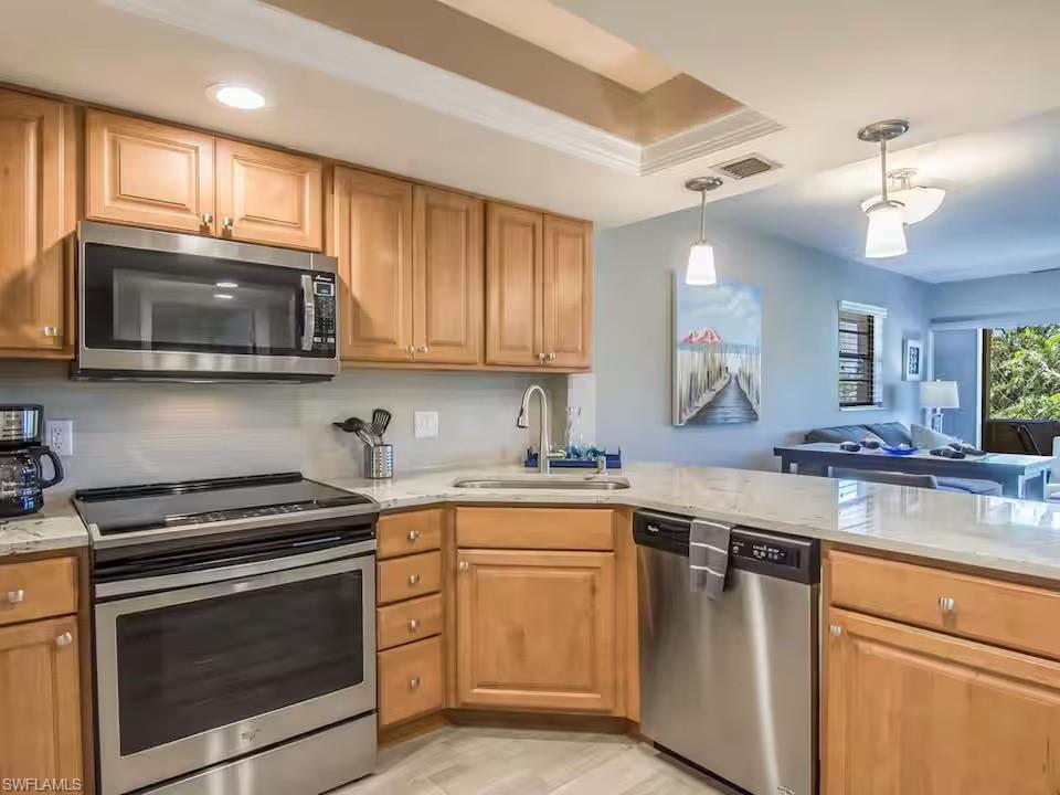 600 Neapolitan Way, Unit 341 Naples, FL 34103 - Photo 8 of 28 a kitchen with stainless steel appliances granite countertop wooden cabinets stove top oven a sink and dishwasher