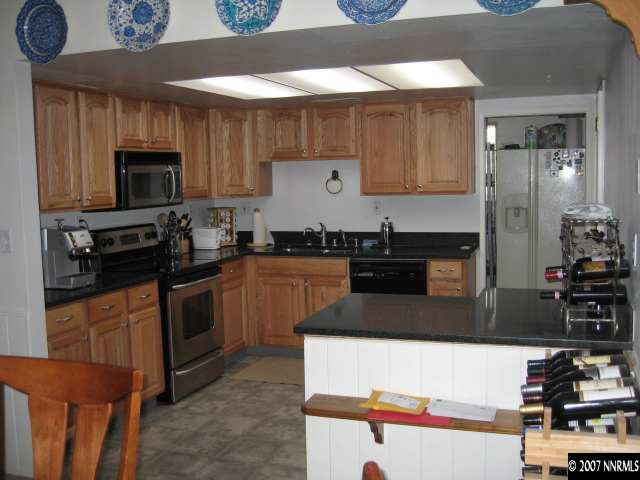 8655 Channel Way Reno, NV 89506 - Photo 3 of 5 a kitchen with stainless steel appliances wooden cabinets and a sink