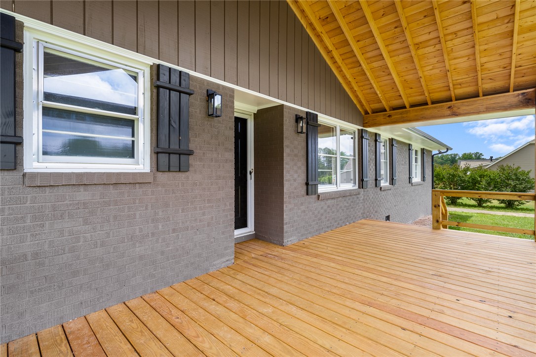 300 Vandiver Road Anderson, SC 29621 - Photo 4 of 30 A spacious wooden deck provides ample outdoor living space, complementing the classic brick exterior and shuttered windows.
