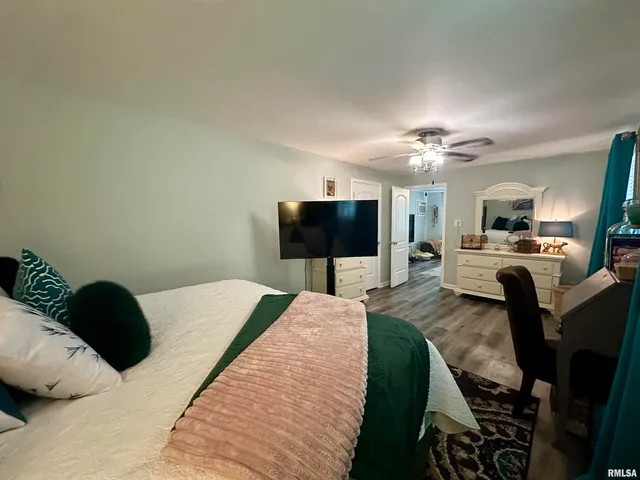 a bedroom with a bed a flat screen tv and a chandelier