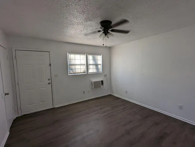 a view of an empty room with a window and wooden floor