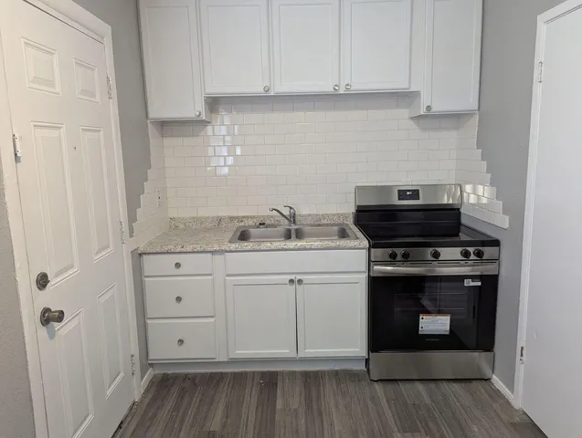 a kitchen with granite countertop white cabinets and black appliances