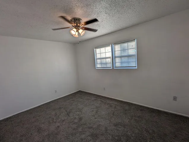 a view of an empty room with a chandelier fan