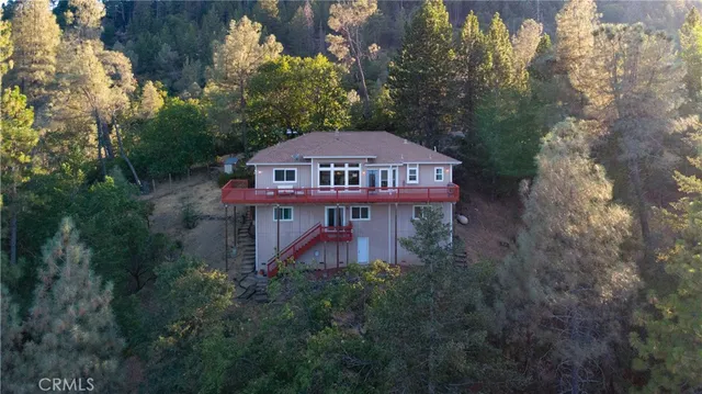 a view of a big house with big yard plants and large trees