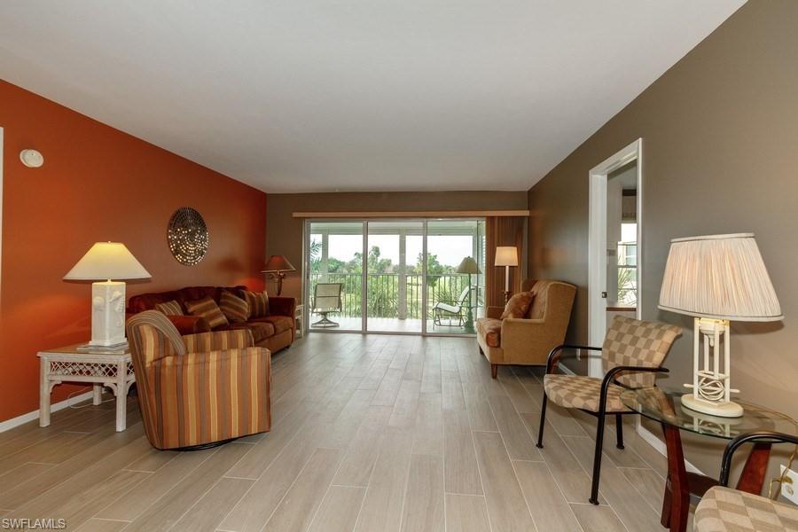 200 Pebble Beach Boulevard, Unit D402 Naples, FL 34113 - Photo 3 of 14 a living room with furniture and a lamp