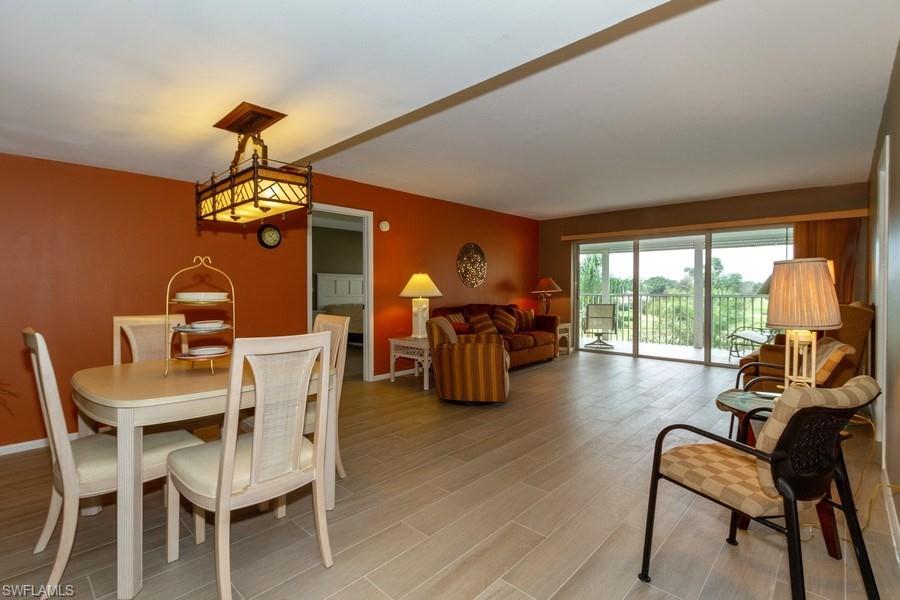 200 Pebble Beach Boulevard, Unit D402 Naples, FL 34113 - Photo 4 of 14 a dining room with furniture a chandelier and wooden floor