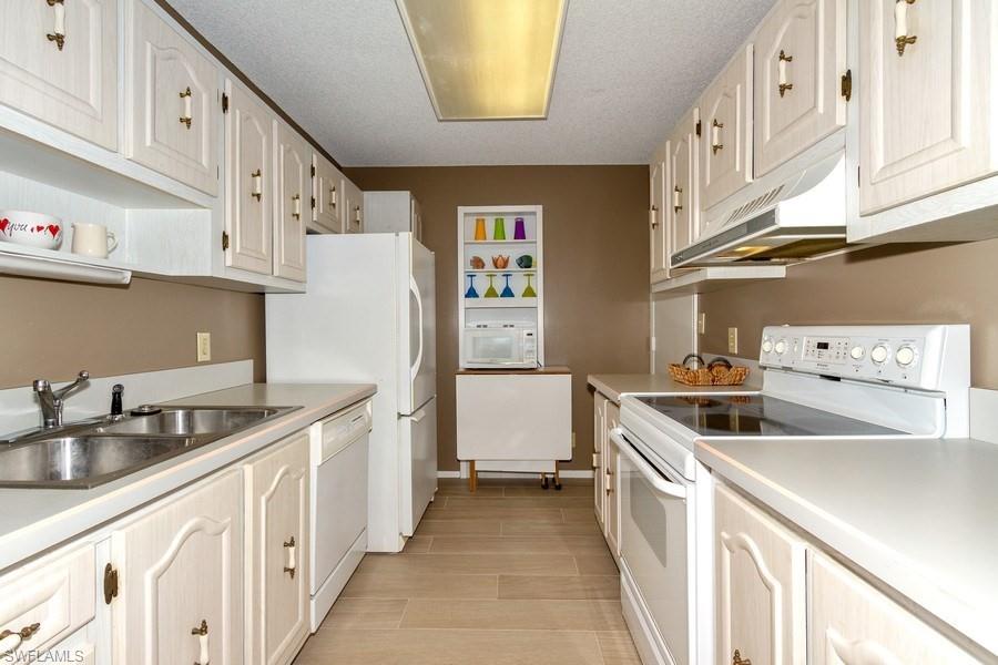 200 Pebble Beach Boulevard, Unit D402 Naples, FL 34113 - Photo 5 of 14 a kitchen with stainless steel appliances granite countertop a sink and a refrigerator