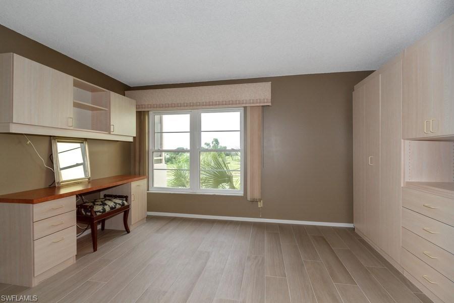 200 Pebble Beach Boulevard, Unit D402 Naples, FL 34113 - Photo 7 of 14 a view of an empty room with a window and wooden floor