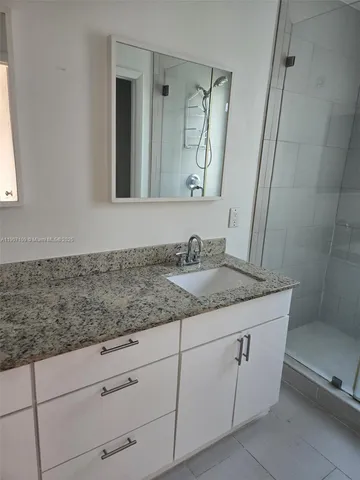a bathroom with a granite countertop sink and mirror