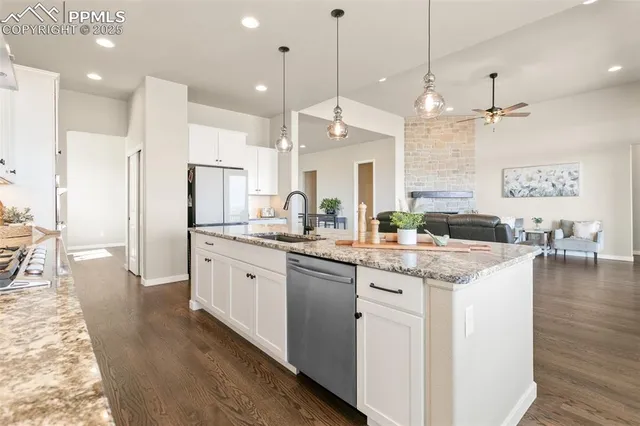 a kitchen with stainless steel appliances granite countertop a sink a stove a refrigerator and island with wooden floor