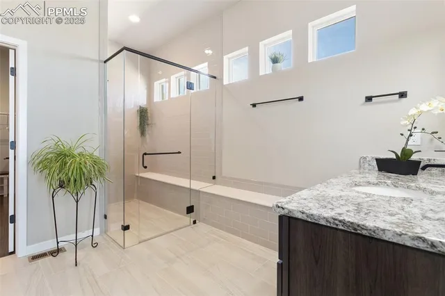 a bathroom with a granite countertop sink a mirror and shower