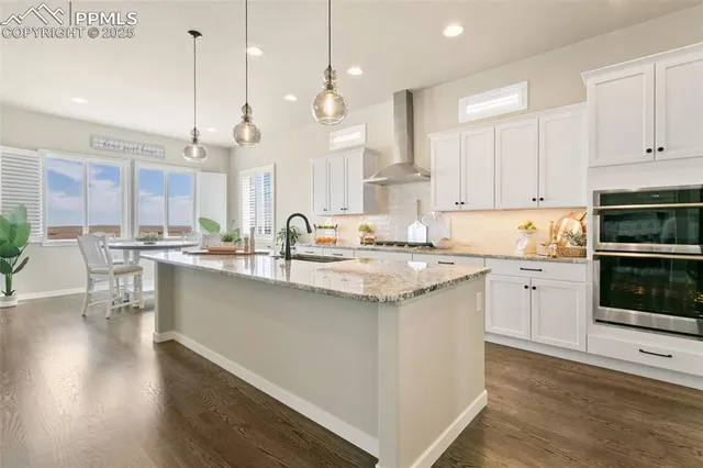 a kitchen with stainless steel appliances granite countertop a sink a stove and a wooden floors