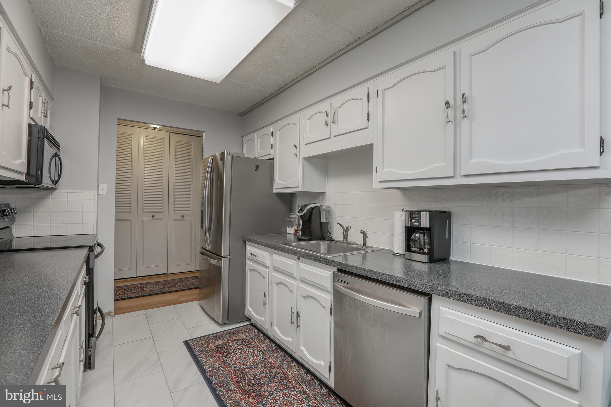 860 Lower Ferry Road, Unit 2C Ewing, NJ 08628 - Photo 9 of 19 a kitchen with stainless steel appliances granite countertop a refrigerator sink and white cabinets
