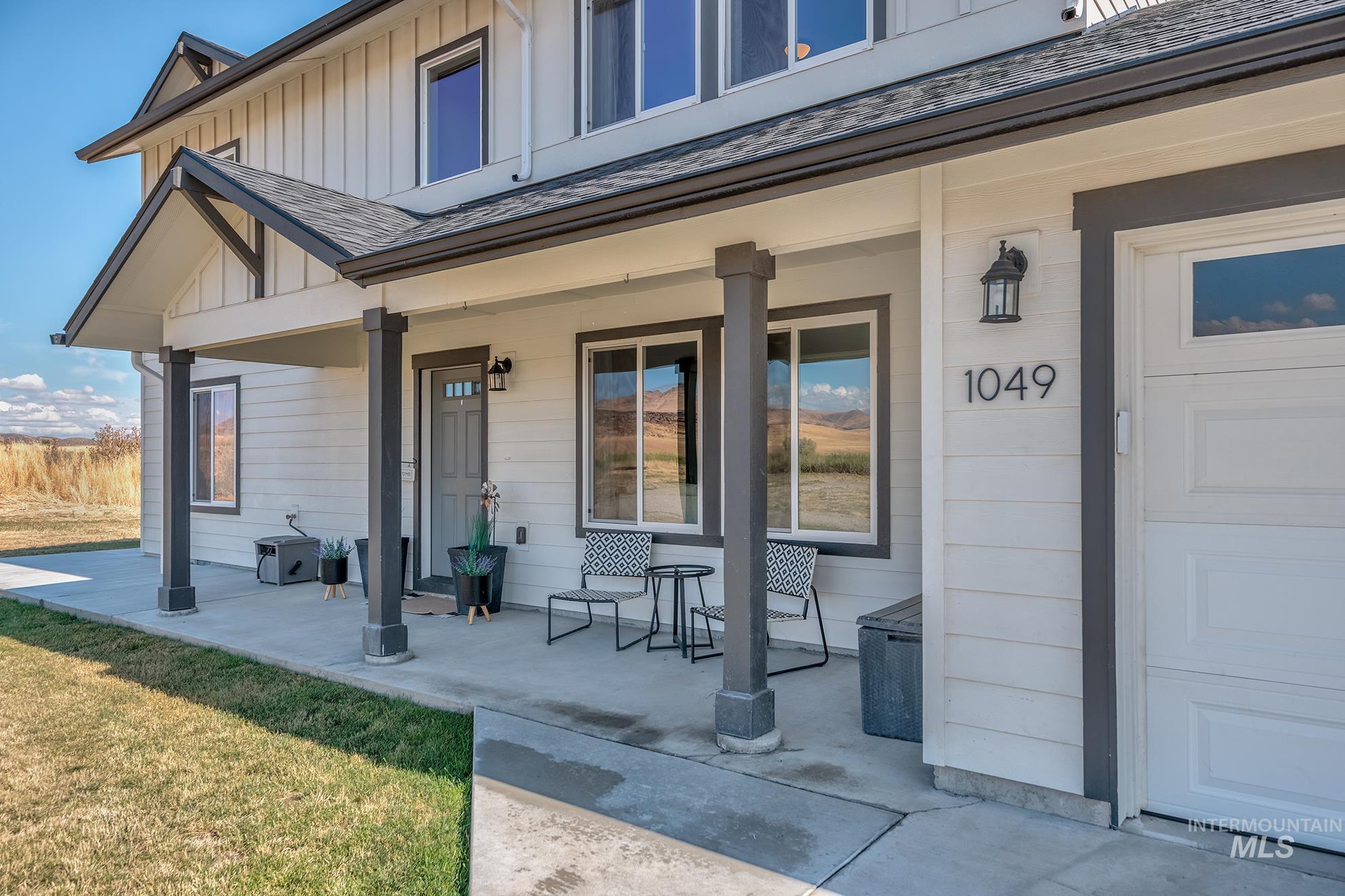 1049 Price Road Weiser, ID 83672 - Photo 2 of 47 Two-story residential exterior featuring a covered porch with dark-toned columns, white siding, and dark trim details