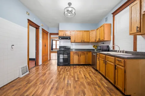 a kitchen with stainless steel appliances granite countertop a refrigerator a sink dishwasher a stove and white countertops with wooden floor