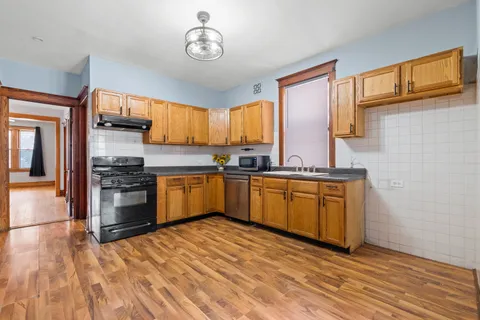a kitchen with stainless steel appliances granite countertop a stove a sink dishwasher and a refrigerator with wooden floor