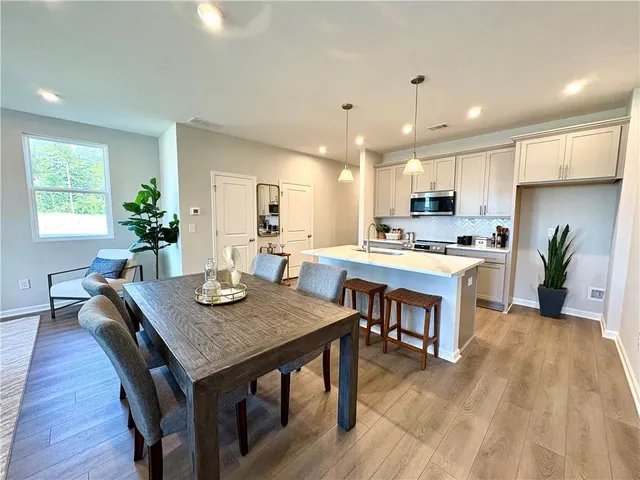 a kitchen with stainless steel appliances granite countertop a refrigerator a sink dishwasher a stove and white cabinets with wooden floor