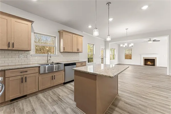 a kitchen with stainless steel appliances granite countertop hardwood floor sink stove and wooden cabinets