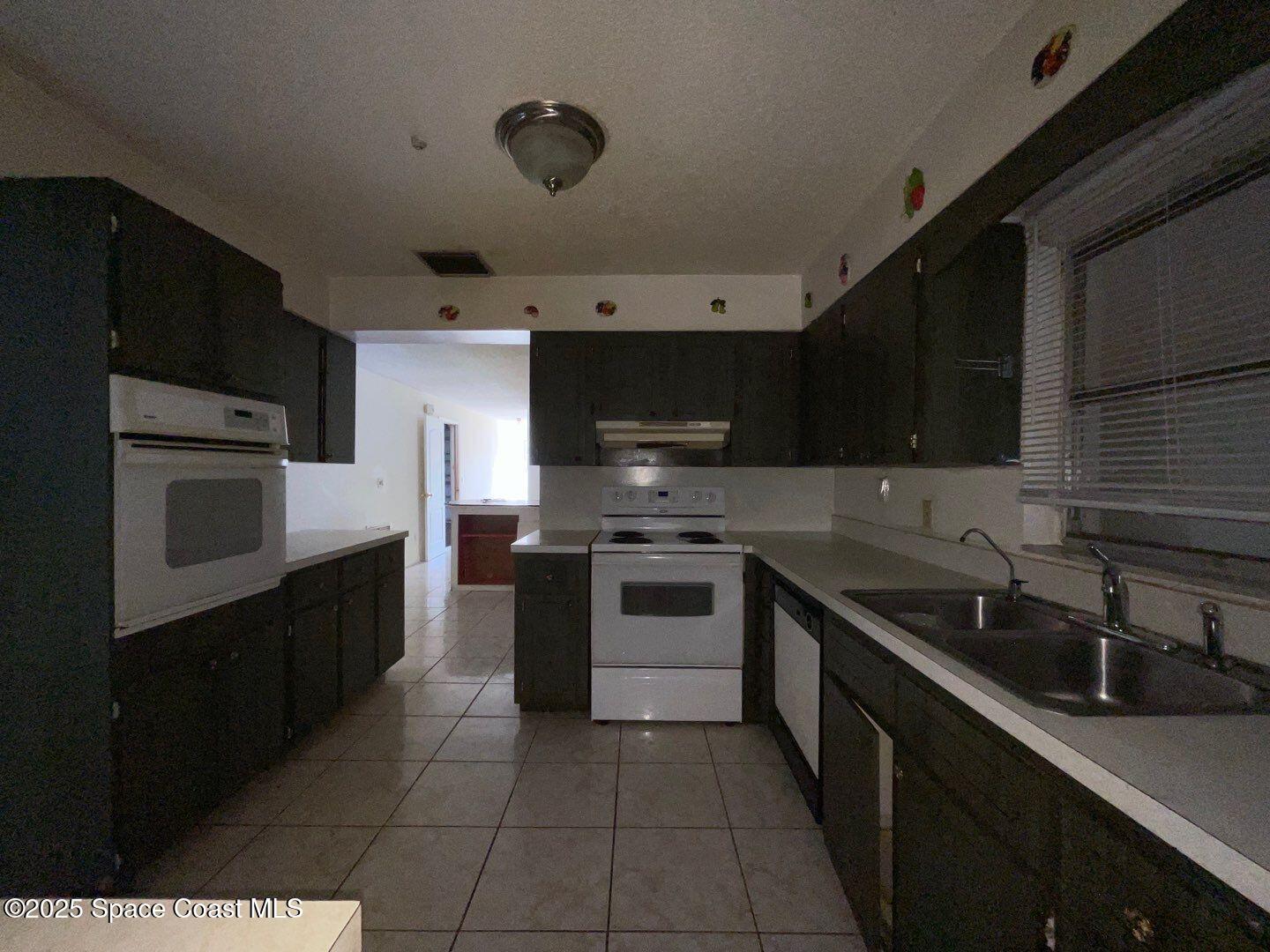 617 Walker Street Melbourne, FL 32901 - Photo 9 of 38 a kitchen with stainless steel appliances a sink dishwasher a stove top oven a refrigerator and cabinets