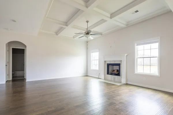 an empty room with wooden floor fireplace and windows