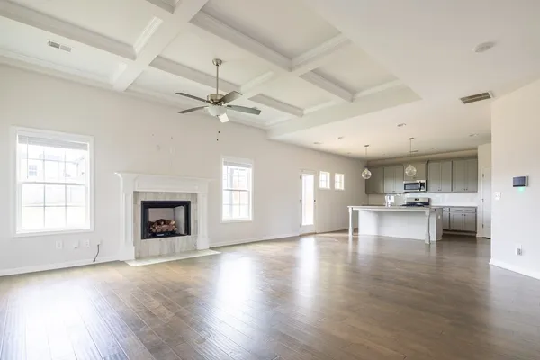 a view of an empty room with a kitchen and a fireplace