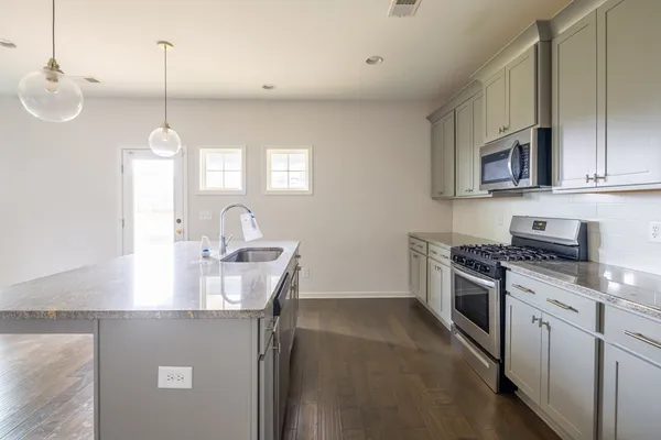 a kitchen with stainless steel appliances granite countertop a sink a stove and a refrigerator